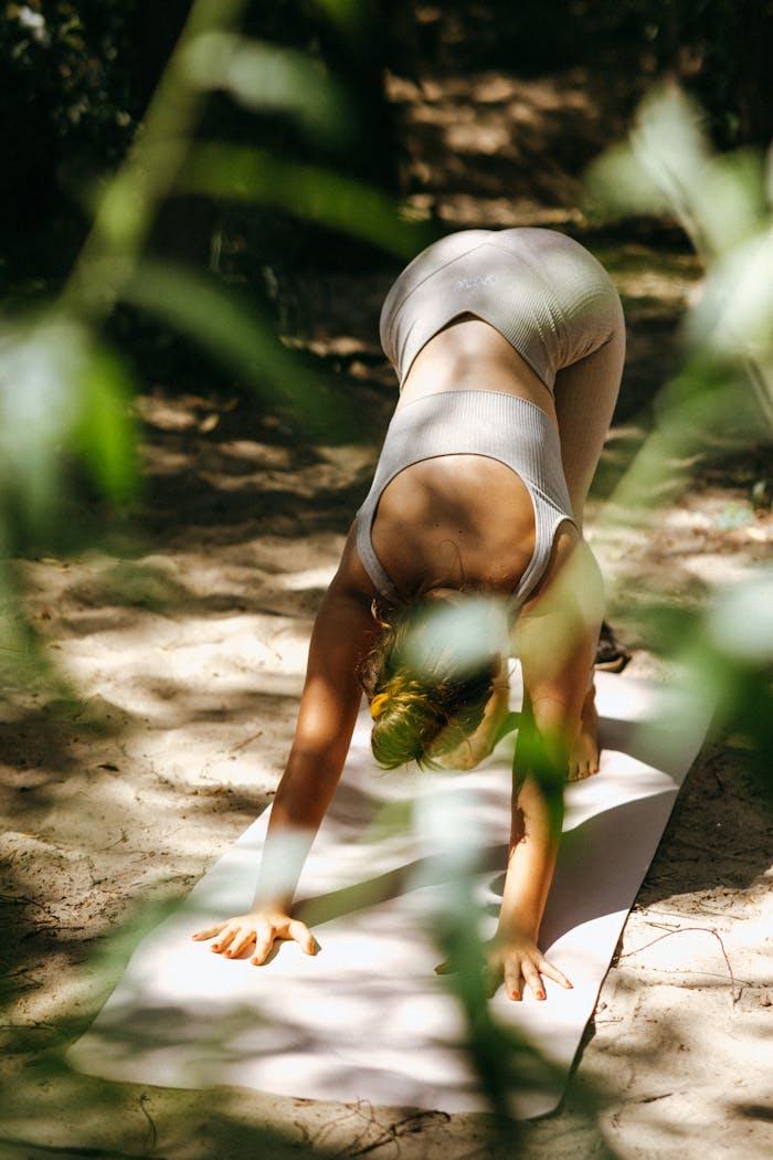 A woman doing yoga in a serene outdoor forest setting, focusing on wellness and flexibility.